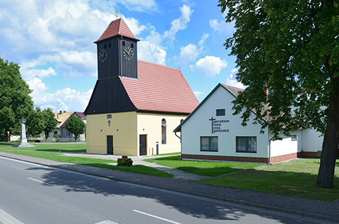 kleine Kirche mit rotem Ziegeldach, daneben das Gemeindehaus