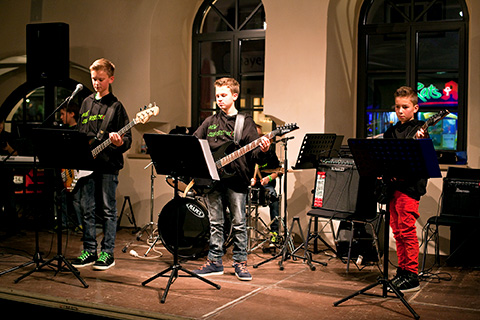 <p>
	jugendliche Musiker auf der Bühne, im Vordergrund drei Jungs mit E-Gitarren</p>
